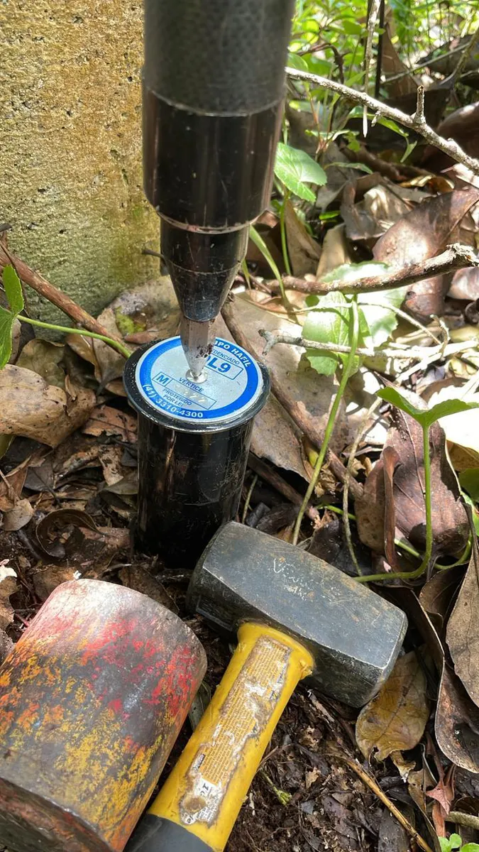 Marco com plaqueta sendo cravado no solo